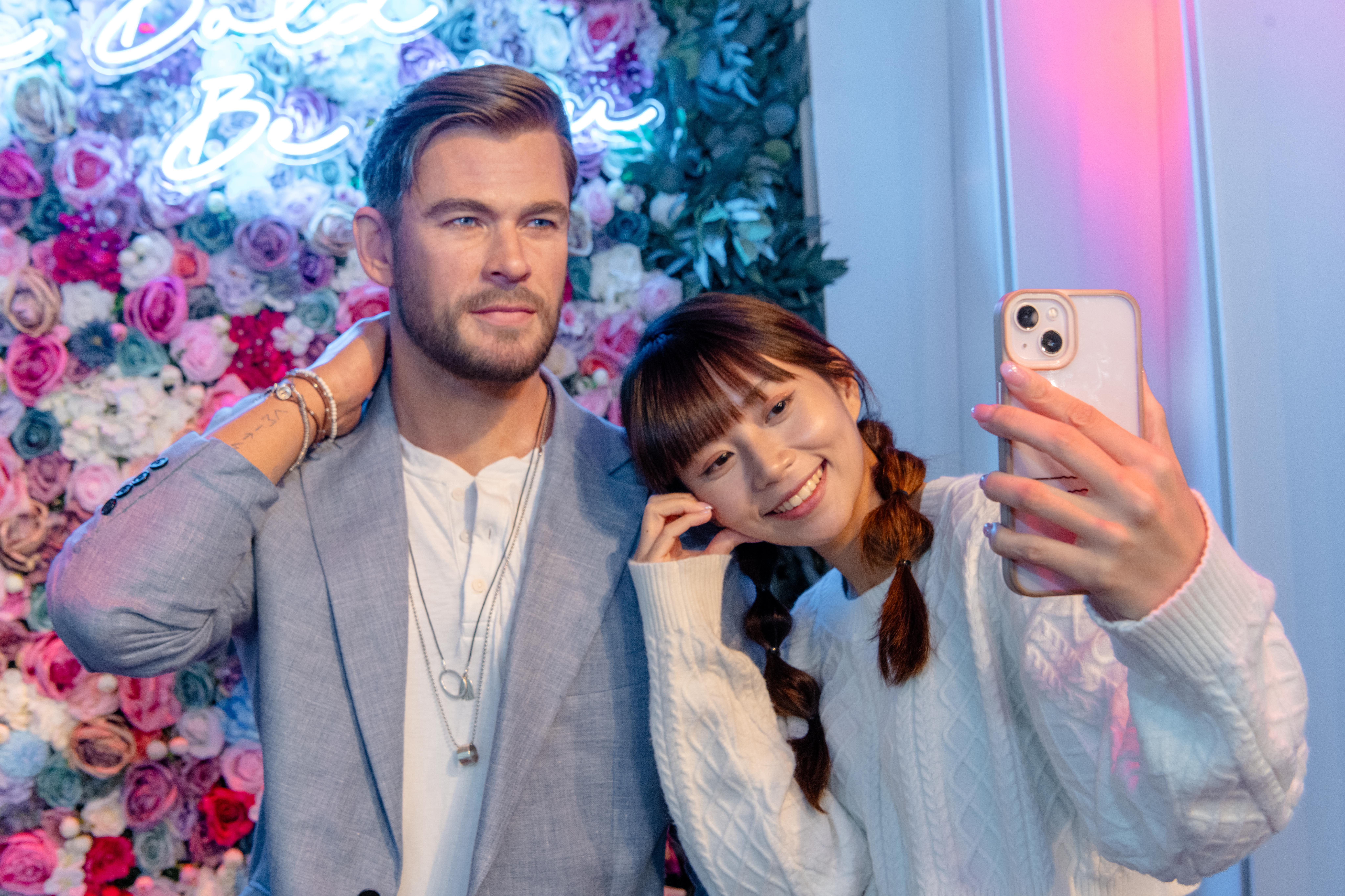 Chris Hemsworth wax figure in front of floral wall