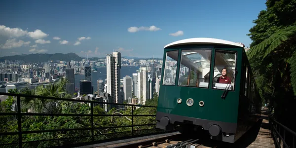 A green Peak Tram ascending the picturesque hills of Hong Kong, providing a scenic ride to the highest point on Hong Kong Island. Passengers aboard are treated to awe-inspiring panoramic views of the city skyline and Victoria Harbour.
