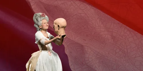 Wax figure of Madame Tussaud wearing a white Victorian-style dress with a high neckline and intricate lace detailing. She is holding a wax mold of a head with both hands, looking towards it with a joyful expression.