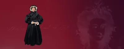 Wax figure of Madame Tussaud depicted wearing a black Victorian-style dress with intricate lace detailing and a high collar. The dress is incredibly detailed with folds and layers, making it a lifelike representation of Madame Tussaud in her Victorian era attire.