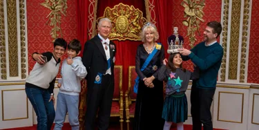 Family taking group photo with the royal family wax figures
