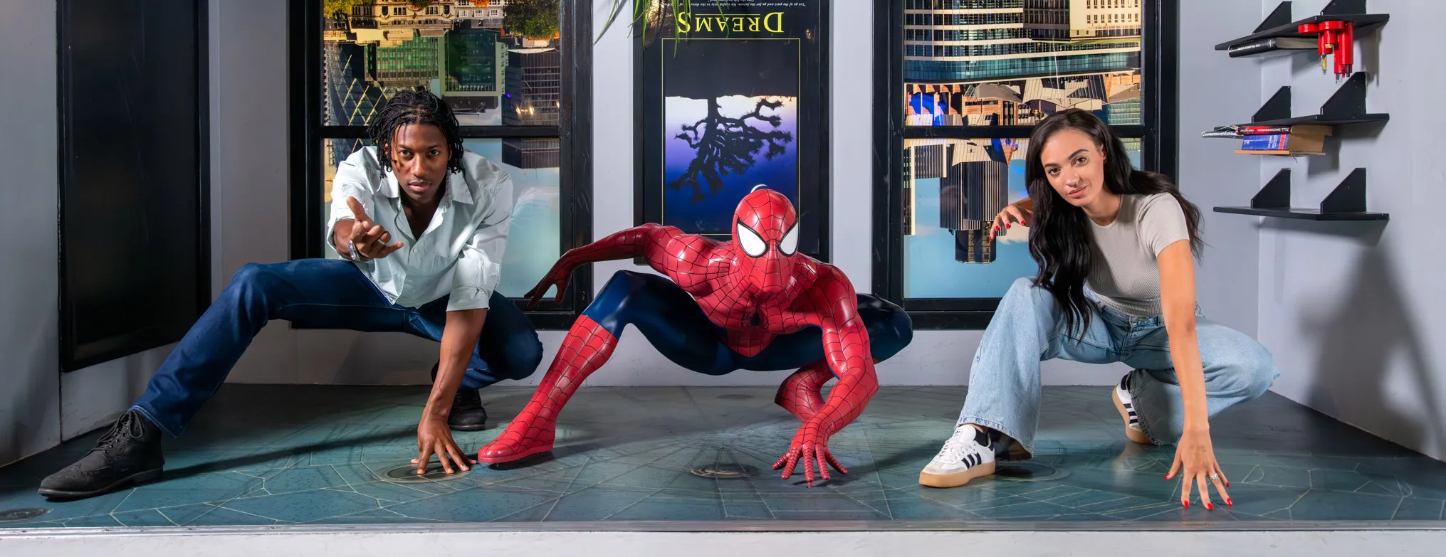 Two people posing alongside Spiderman in a bedroom set