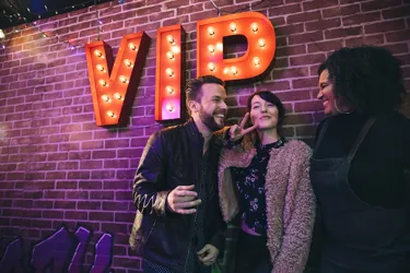 Group of friends standing in front of the VIP lighted sign, enjoying their Ultimate Inclusive ticket package at the World Famous Wax Museum, Madame Tussauds New York.