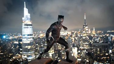Black Panther wax figure on NYC rooftop with city skyline at night.