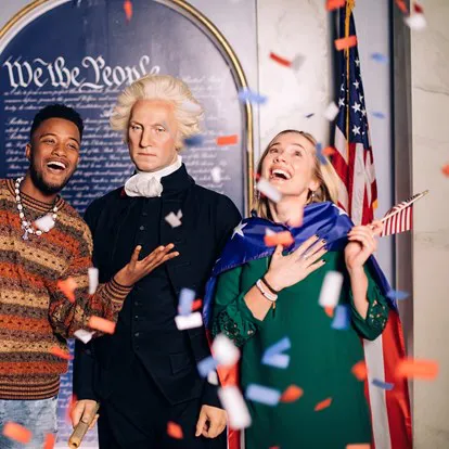 Guests posing with a wax figure of George Washington and confetti is falling down