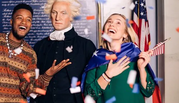 Guests posing with a wax figure of George Washington and confetti is falling down
