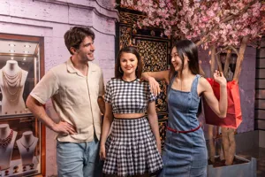 A man and woman laughing and posing with a wax figure of Selena Gomez at Madame Tussauds New York
