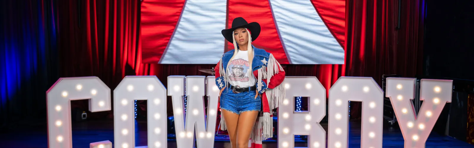 Madame Tussauds Orlando’s wax figure of Beyoncé posing in front of glowing 'COWBOY' letters.