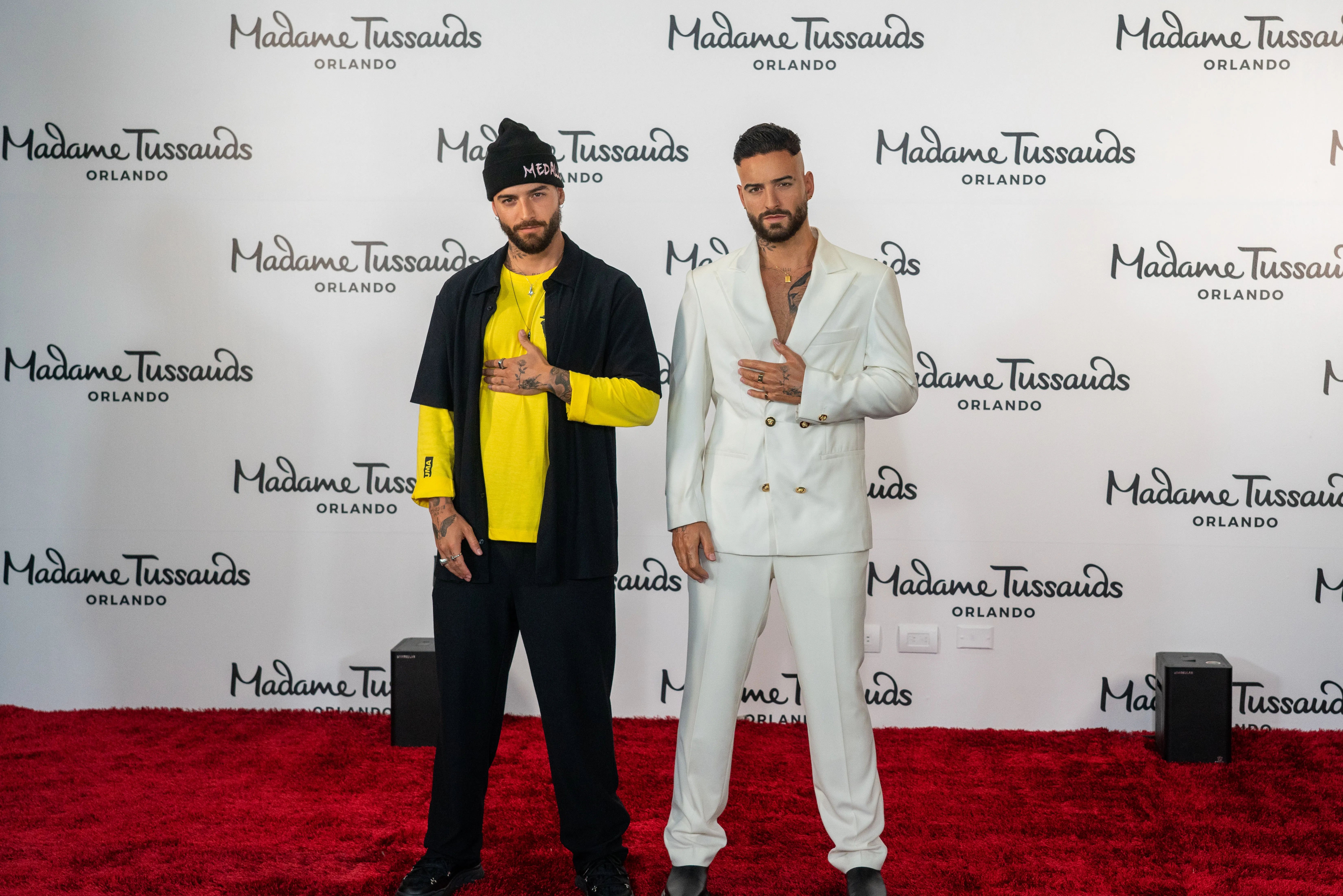 Maluma poses beside his Madame Tussauds Orlando wax figure, both dressed in stylish outfits.