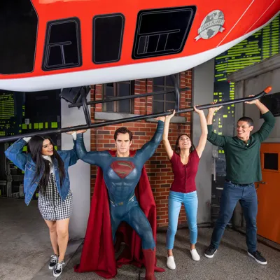 Guests pose with Superman wax figure holding up a prop helicopter