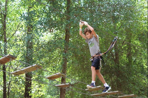 A young visitor walking on a suspended bridge at Tree Trek Adventure Park Orlando