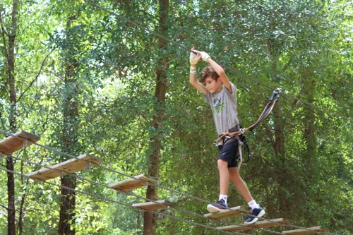 A young visitor walking on a suspended bridge at Tree Trek Adventure Park Orlando