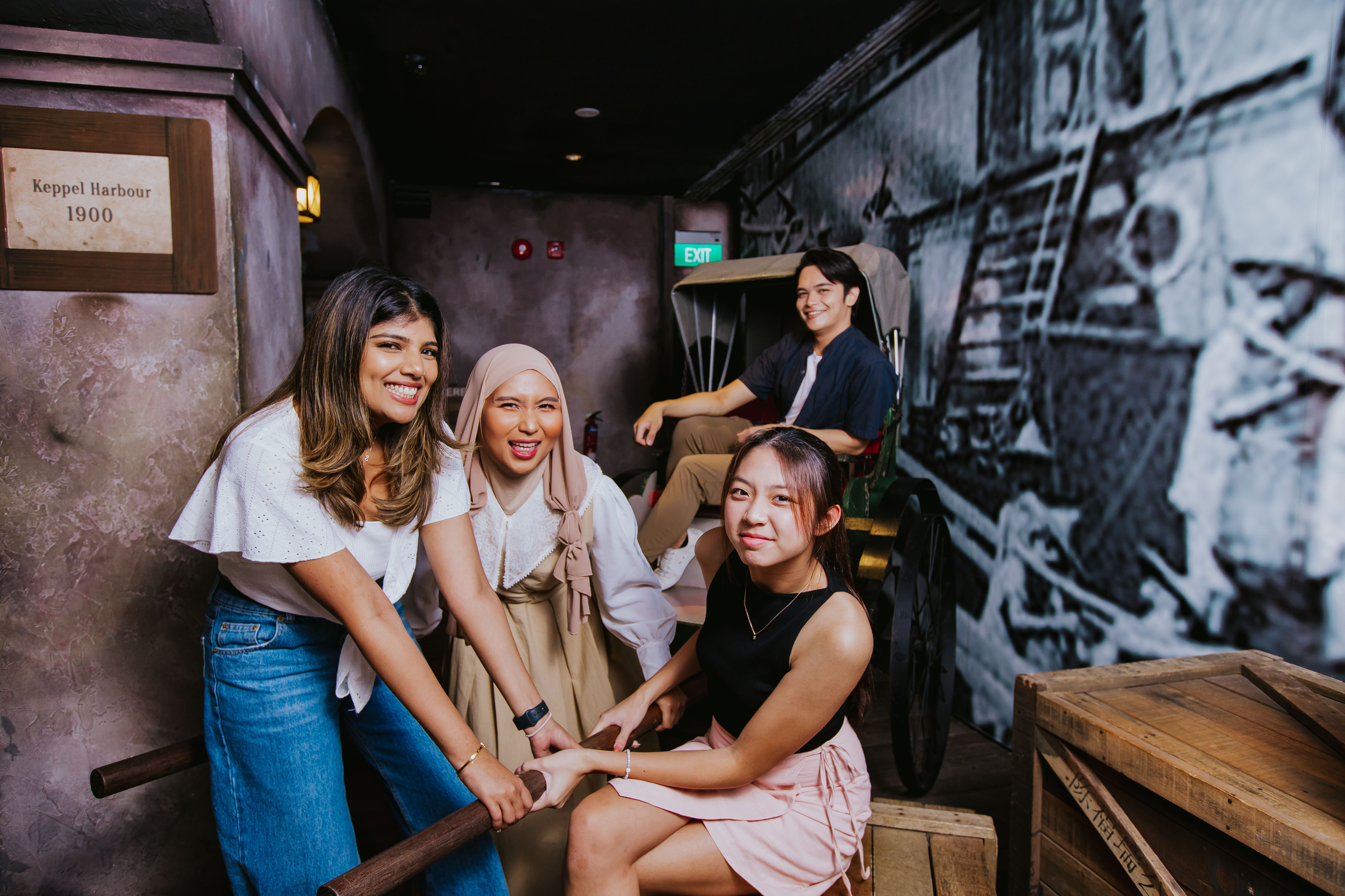 As part of Images of Singapore exhibition in Madame Tussauds, 3 girls pretended to pull a rickshaw as a pose for a photo. A guy sat on a the rickshaw seat.
