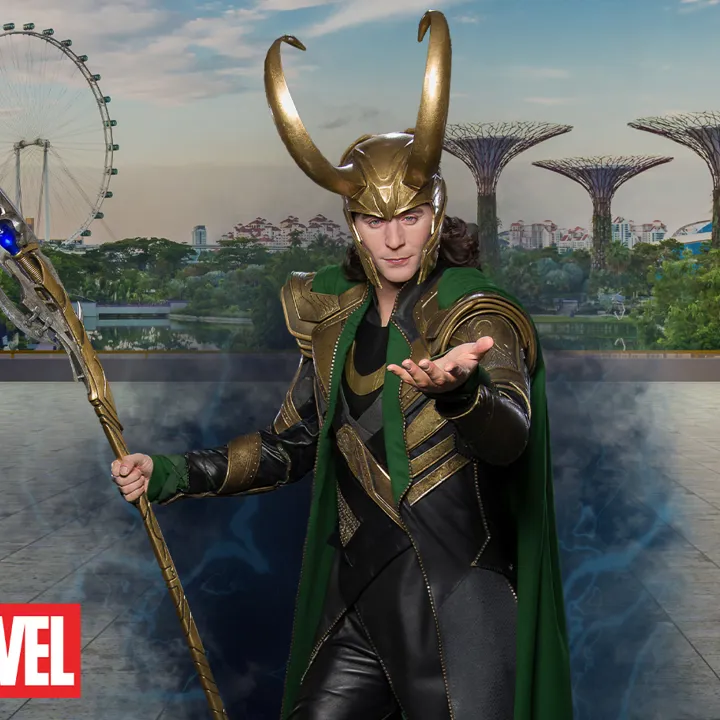 Madame Tussauds Singapore's wax figure of Loki from the Marvel Cinematic Universe, portrayed by actor Tom Hiddleston, wearing his signature green and gold costume and standing confidently with a mischievous expression