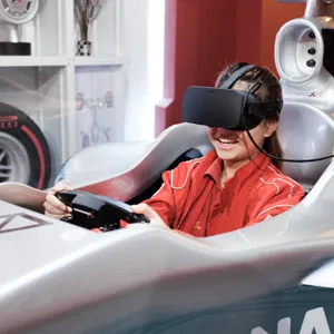 Virtual reality racing experience at Madame Tussauds Singapore - A person wearing a VR headset sitting in a racing seat with a steering wheel and pedals
