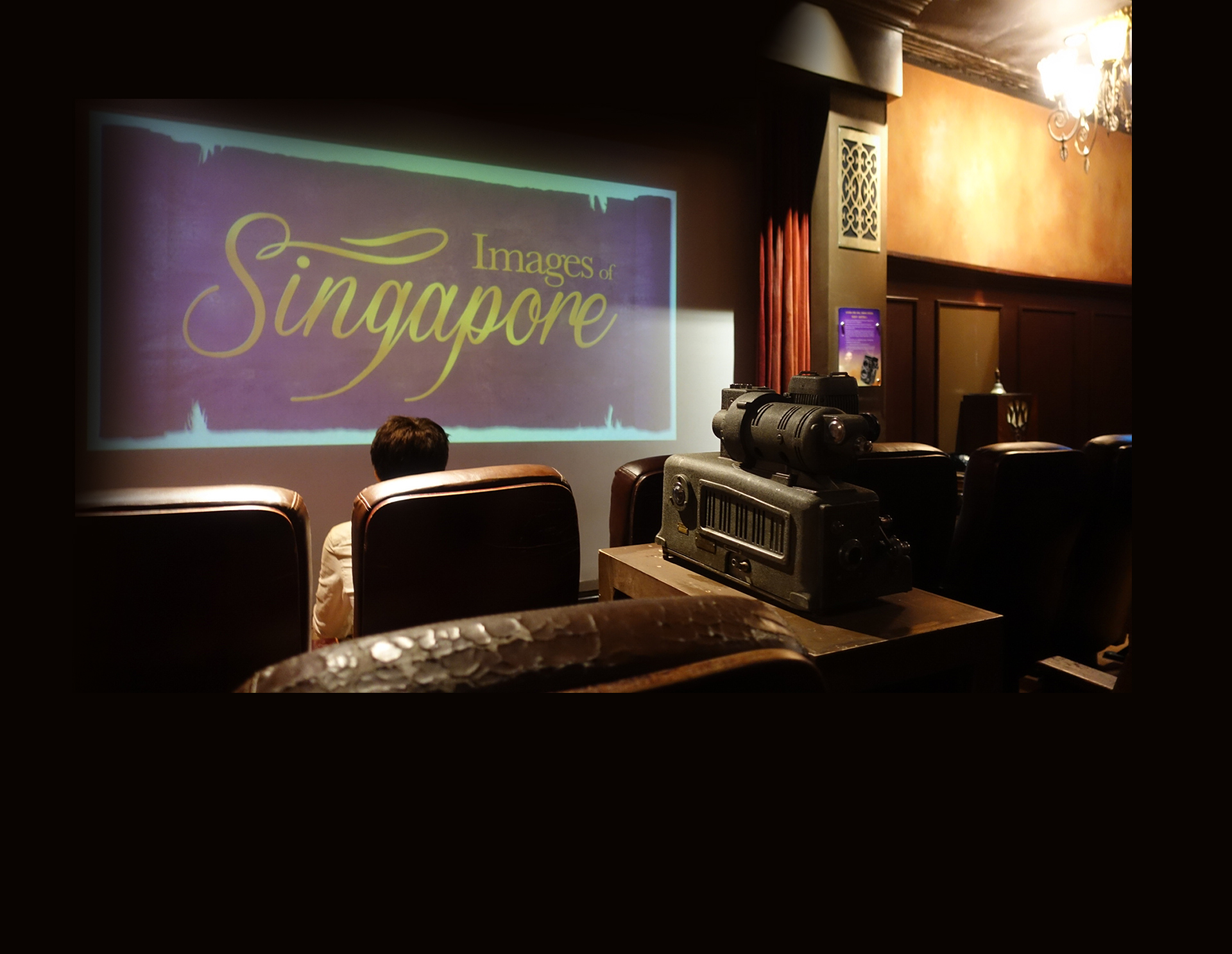 As part of Images of Singapore exhibition in Madame Tussauds, a person is sitting on a big sofa in a room that recreates Jubilee Cinema setup, complete with an old film projector.