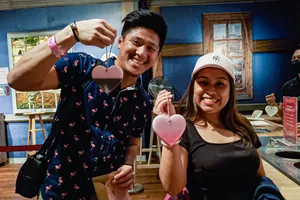 Two people holding a heart-shaped wax that's hanging on a brown thread, as part of wax dipping workshop in Madame Tussauds Singapore