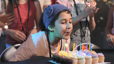 child blowing out candles on cake