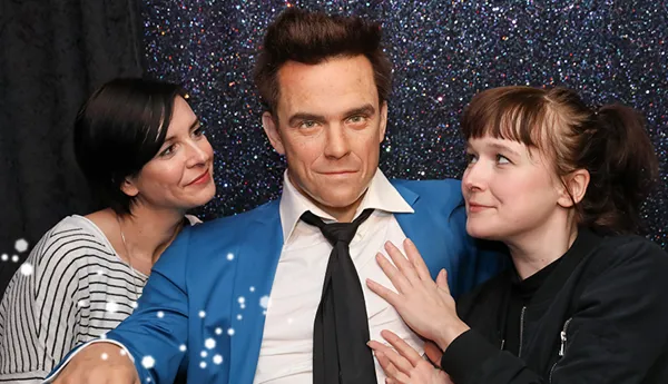 Zwei Fans mit der Wachsfigur von Robbie Williams im Madame Tussauds Wien